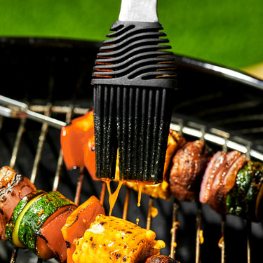 The HexClad BBQ braiser being used on kebab skewers on a grill.