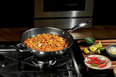 A dish featuring noodles in a pan on a gas stovetop.