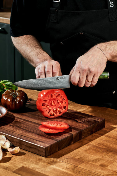 A person slicing a heirloom tomato with a HexClad knife.
