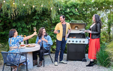 A group of friends standing around an outdoor grill.