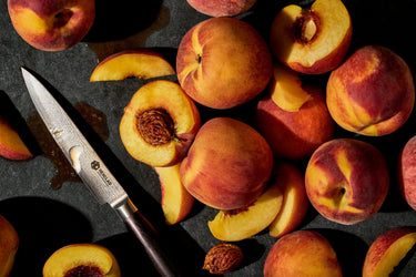 HexClad Espresso Utility Knife Next To An Array of Fresh Peaches